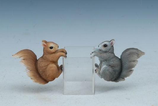 Two squirrel figurines, one brown and one gray, hanging from an empty planter against a light blue background.