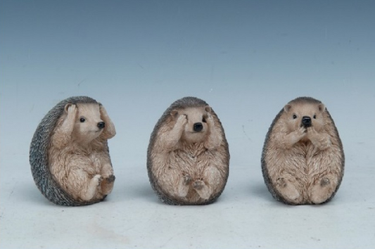 Three hedgehog figurines making 'see no evil, hear no evil, speak no evil' gestures on a light blue background.