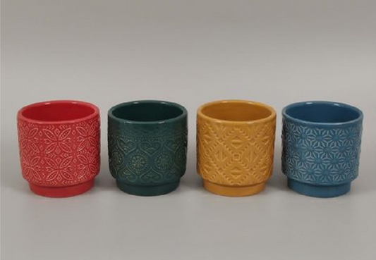 Four ceramic pots with textured patterns in red, green, yellow, and blue on a light gray background.